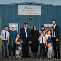 Tareq Hadhad, owner of Peace by Chocolate, standing proud in front of the store front with his Syrian family.