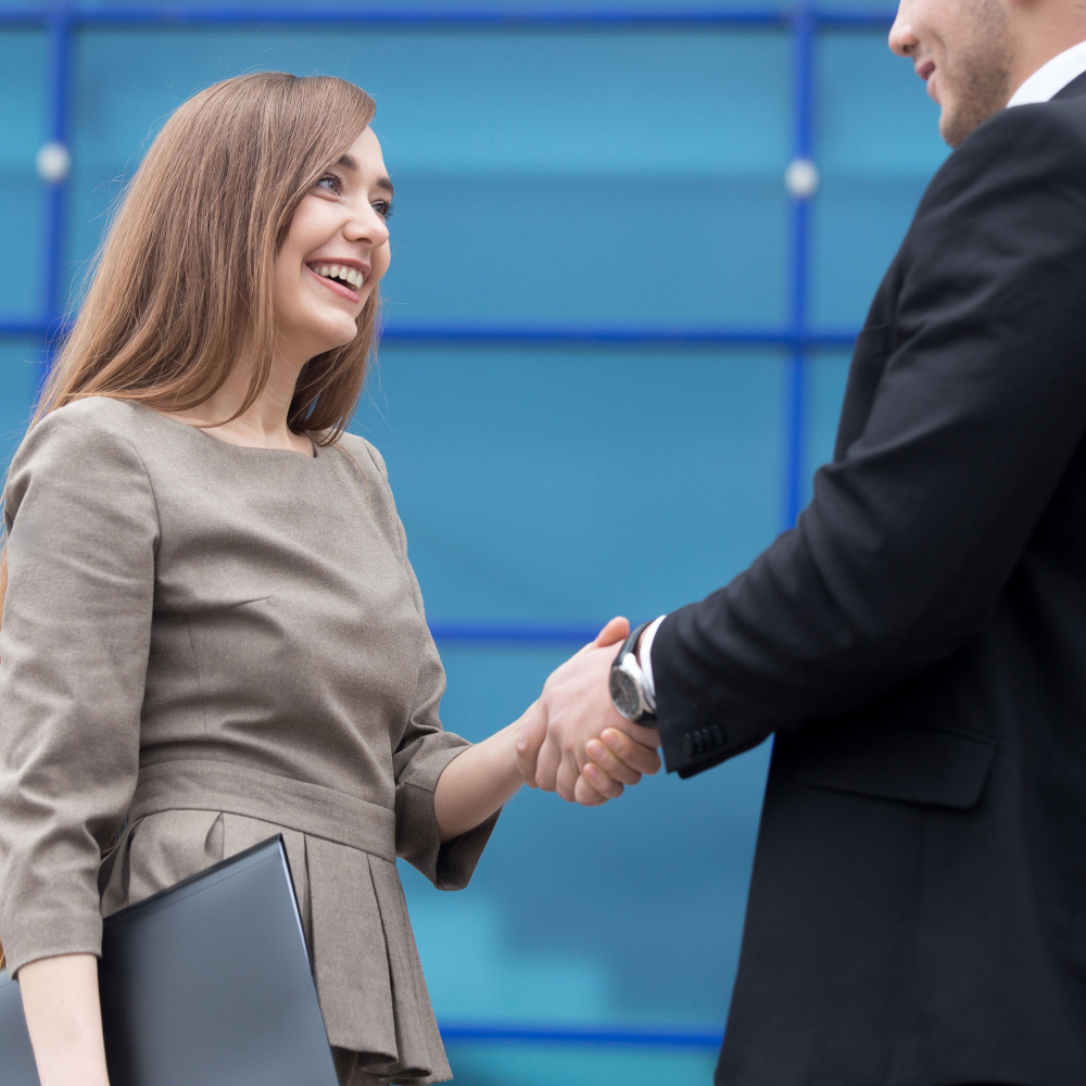 Successful business people shaking hands for greeting or in agreement happy to work together. Focus on smiling businesswoman.
