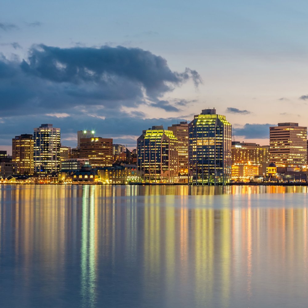 Panoramic Skyline of Halifax City illuminated at night reflecting in the water of Halifax harbour.